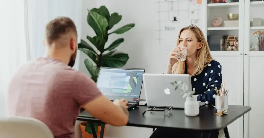 Dos emprendedores comparando opciones empresariales mientras trabajan frente a frente con sus laptops, representando la diferencia entre una LLC y una SRL en República